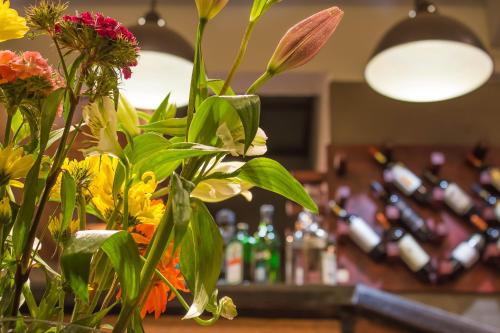 a vase of flowers on a counter with bottles of alcohol at Hotel Boutique 17 in Valparaíso