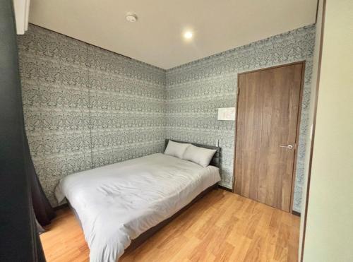 a small bedroom with a bed and a door at HoTTOSTAY旭 in Nishi-biwajima