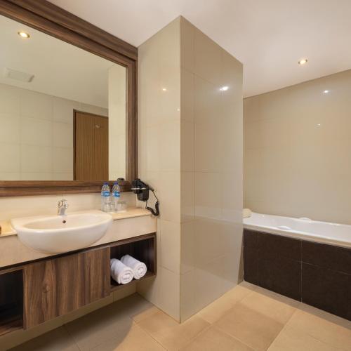a bathroom with a sink and a shower and a tub at Crystalkuta Hotel - Bali in Kuta