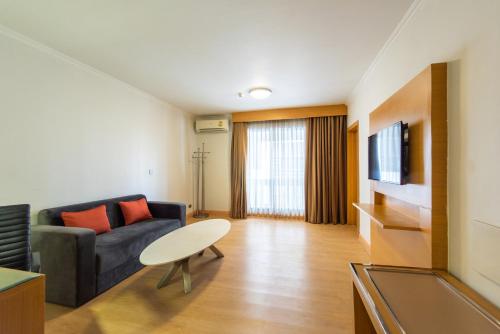 a living room with a couch and a tv at Maple Hotel in Bangkok