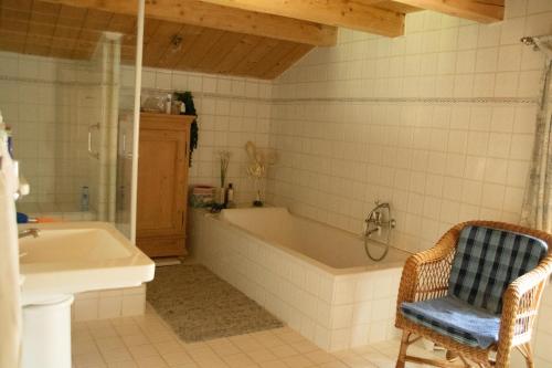 a bathroom with a tub and a chair and a sink at Bauernhaus auf dem Land in Hebertsfelden