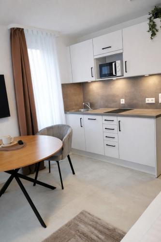 a kitchen with white cabinets and a wooden table at Sindelfingen Apartments in Sindelfingen