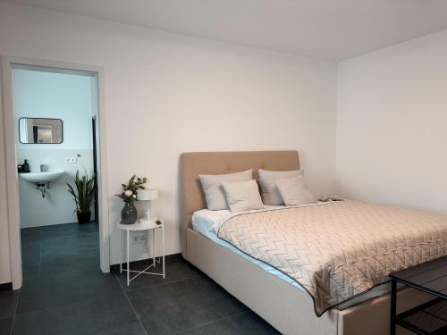 a white bedroom with a bed and a sink at Comfort Apartment Midami in Schwanau