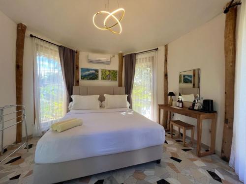 a bedroom with a large white bed and windows at Madasari Village in Madasari