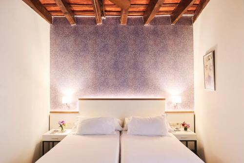 a bedroom with a white bed with two tables at H10 Raco del Pi Boutique hotel in Barcelona