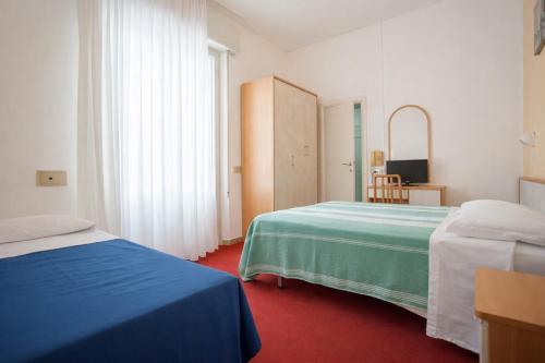 a hotel room with two beds and a mirror at Villa Silvie Rose in Cesenatico
