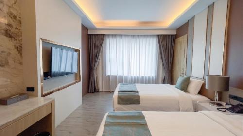 a hotel room with two beds and a flat screen tv at Enrich Grand Hotel in Bangkok