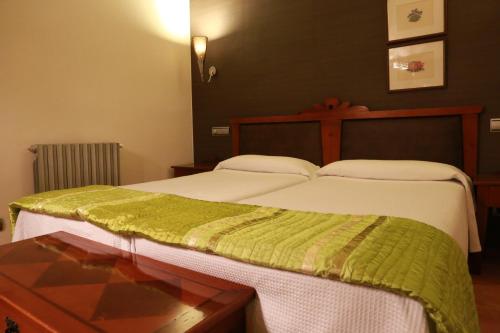 a bedroom with a bed with a green blanket on it at Hospederia de Loarre in Loarre