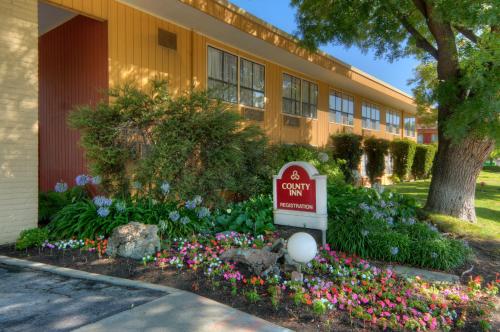 a sign in front of a building with flowers at County Inn in Mountain View