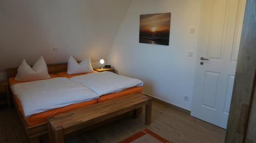 a small bedroom with a bed with a bench in it at Reethaus Casa Baltica in Börgerende-Rethwisch