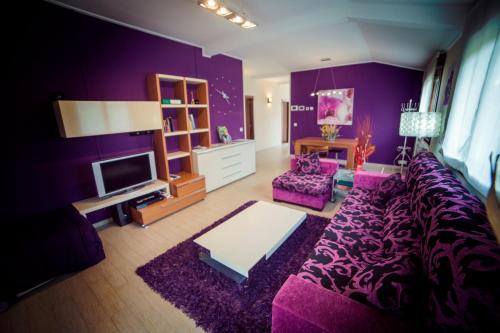 a purple living room with a couch and a tv at El Mirador de la Toba in Fuentetoba