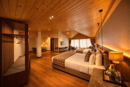 a hotel room with two beds and a desk at Pride Premier Darjeeling in Darjeeling