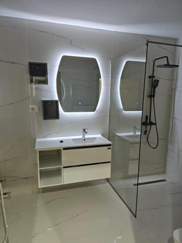 a white bathroom with a sink and a shower at Dino Saraj in Skopje