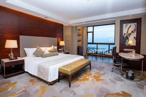 a bedroom with a large white bed and a table at Hotel Nikko Xiamen in Xiamen
