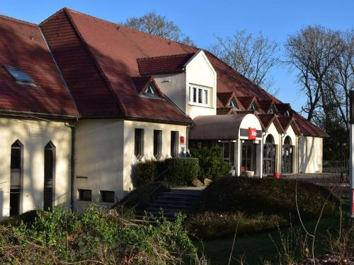 a large white house with a brown roof at Hôtel Ibis Nevers in Nevers