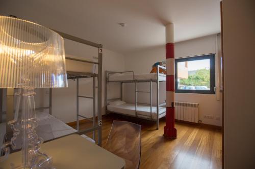 a room with bunk beds and a table and a lamp at HI Alvados - Pousada de Juventude in Alvados