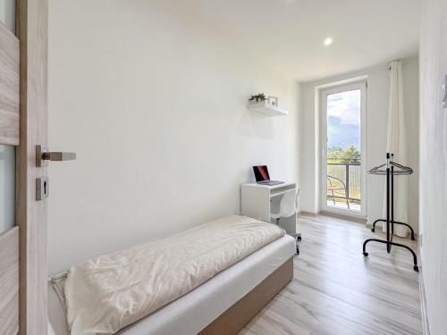 a white bedroom with a bed and a window at Apartmán/byt Liptovský Mikuláš in Liptovský Mikuláš
