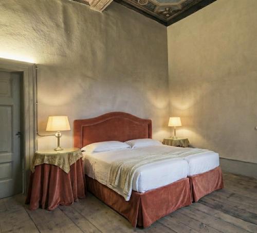 a bedroom with a large bed with two lamps on tables at Palazzo Guicciardi in San Bernardo