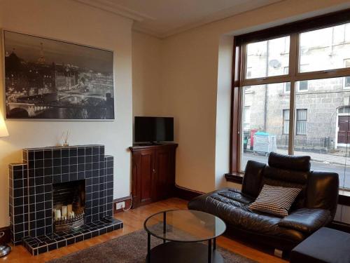a living room with a couch and a fireplace at Apartment Nattan in Aberdeen