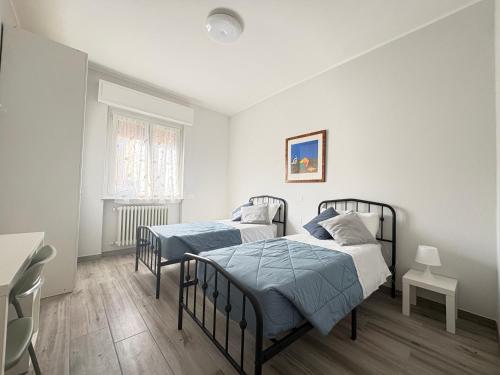 two beds in a room with white walls and wooden floors at Sabo Urban Stay in Grassobbio