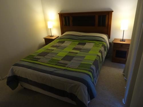a bedroom with a bed with a green blanket on it at TerraBahia Residences in Bahia Inglesa