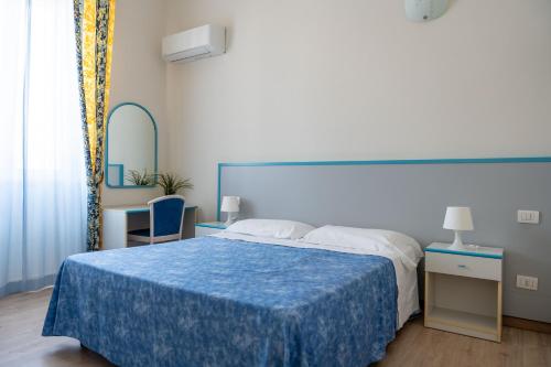 a bedroom with a large bed with a blue blanket at Hotel Centrale in Pineto
