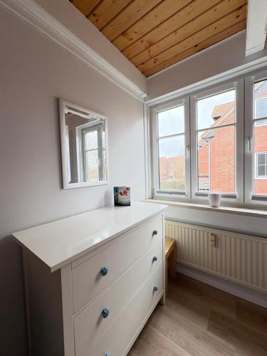 a white dresser in a room with two windows at Ferienwohnung Heimat auf Zeit Pellworm in Pellworm