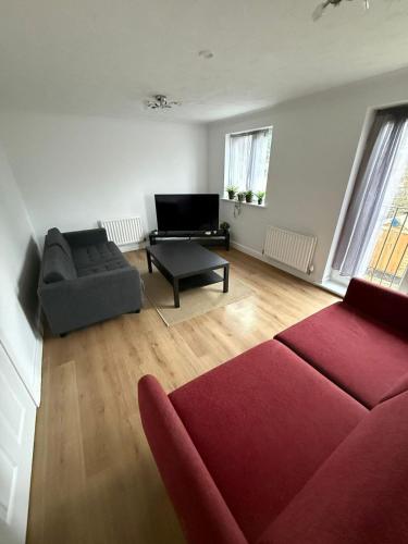 a living room with a red couch and a chair at 4-Bed Contractor Friendly House Long Stays Welcome in Luton