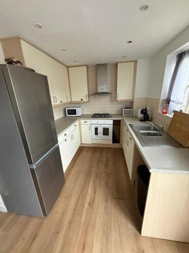 a kitchen with white cabinets and a stainless steel refrigerator at 4-Bed Contractor Friendly House Long Stays Welcome in Luton