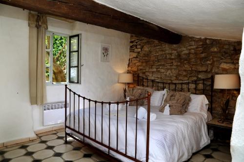 a bedroom with a bed and a stone wall at Château de Villarlong in Villarzel-Cabardès