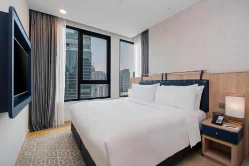 a bedroom with a large white bed and a large window at Staybridge Suites Bangkok Thonglor by IHG in Bangkok