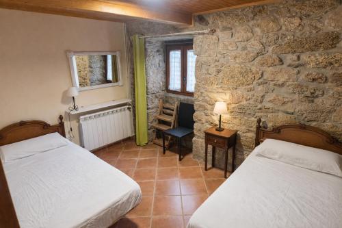 a bedroom with two beds and a stone wall at A Banda do Río in Vilagarcia de Arousa