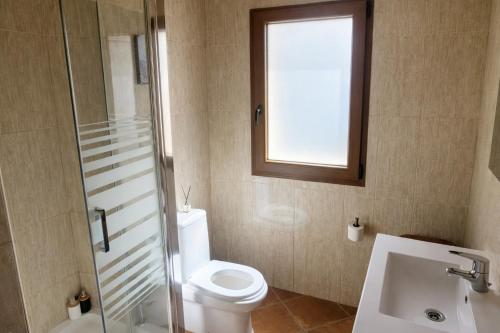 a bathroom with a toilet and a sink and a window at A Banda do Río in Vilagarcia de Arousa