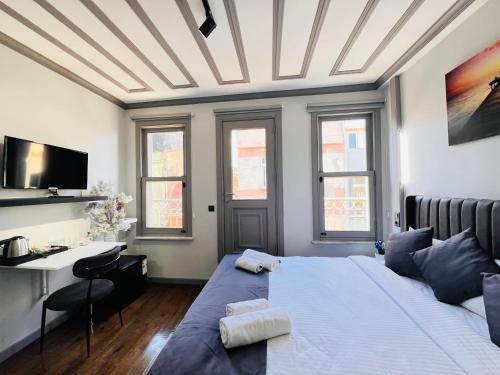 a bedroom with a bed and a desk and windows at Rovigo Hotel in Istanbul