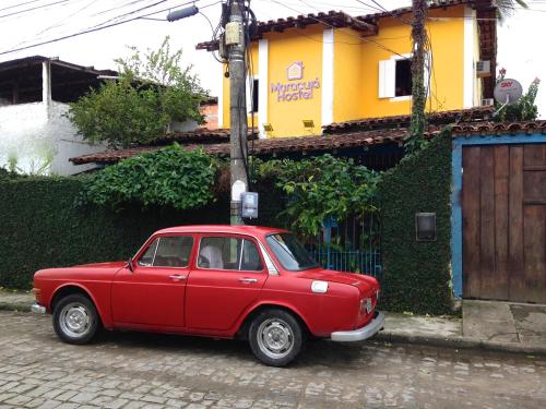 a red car parked in front of a house at Maracujá Hostel in Paraty