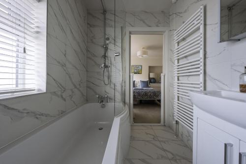 a white bathroom with a tub and a sink at Haven House in Lymington