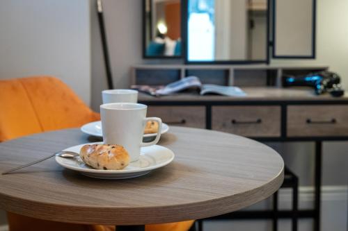 a table with a cup of coffee and a plate of food at Linen Bank Residence - Aparthotel in Linlithgow