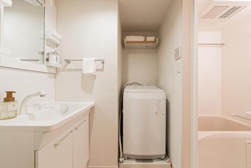 a small white bathroom with a sink and a refrigerator at SAIEI Hotel 东京小岩 JR京成双站直达成田羽田迪士尼适合家庭团队整栋多房型 in Tokyo