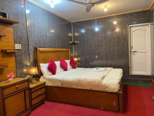 a bedroom with a large bed with red pillows at Ringachan Guest House & Restaurant in Skardu