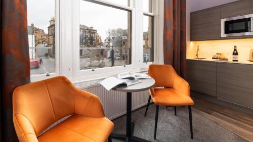 two chairs and a table in a room with a window at Linen Bank Residence - Aparthotel in Linlithgow