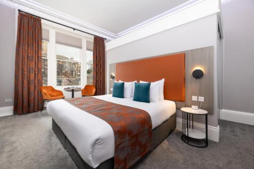 a hotel room with a large bed with blue pillows at Linen Bank Residence - Aparthotel in Linlithgow
