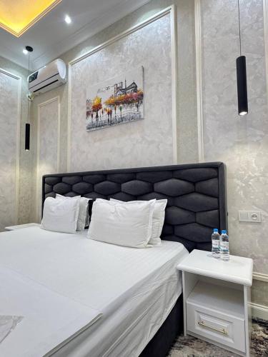 a bedroom with a white bed with a painting on the wall at ANNUR Boutique Hotel in Samarkand