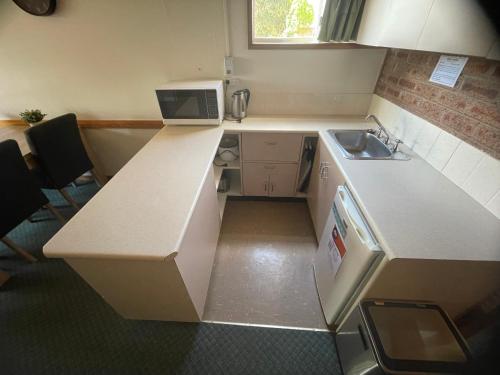 a small kitchen with a sink and a microwave at Alpine Gables Apartment in Jindabyne