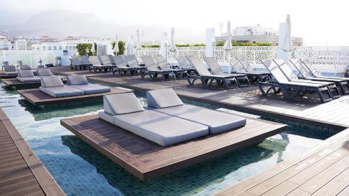 a pool with lounge chairs on a roof at Coral Suites & Spa - Adults Only in Playa de las Americas