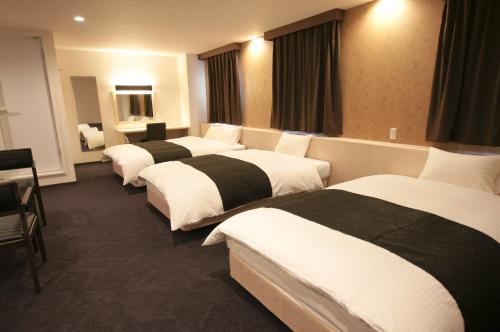 a hotel room with four beds in a room at Miyazaki Daiichi Hotel in Miyazaki