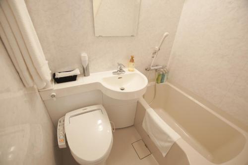 a bathroom with a toilet and a sink and a tub at Miyazaki Daiichi Hotel in Miyazaki