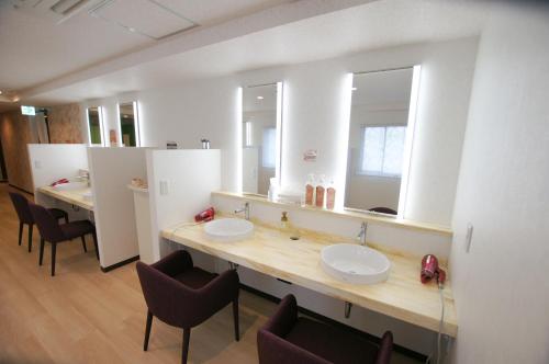 a bathroom with two sinks and two mirrors at Miyazaki Daiichi Hotel in Miyazaki