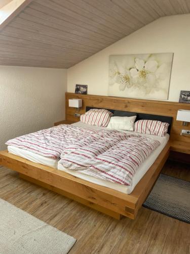 a bedroom with a large wooden bed with two pillows at Ferienwohnung Hörnernest in Bolsterlang