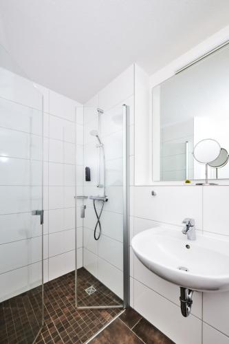 a white bathroom with a sink and a shower at ADAPT APARTMENT HOTEL Giessen in Gießen