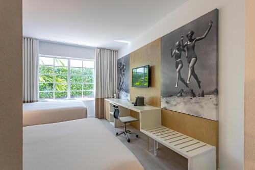 a hotel room with a bed and a desk and a bedroom at Pestana South Beach Miami in Miami Beach